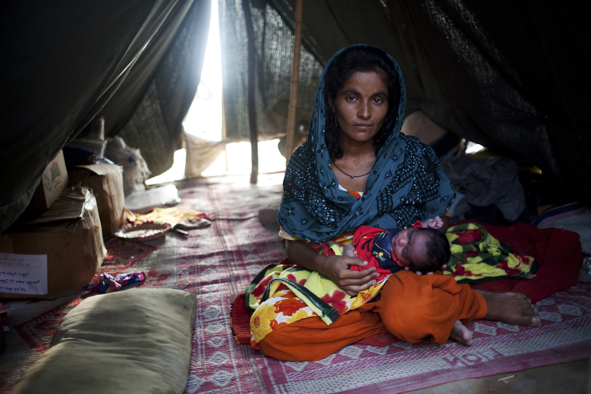 Sonia holds her 3 day old baby girl Sindhu inside her tent at a Pakistan Army run IDP camp in Sehwan Sharif, Sindh Province. She gave birth at a local hospital in Sehwan, where she was referred by medical staff at the camp. Sonia is twenty five years old, and this is her sixth child. September 16, 2010.