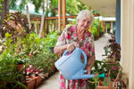Portrait of an assisted living community resident watering her garden plants