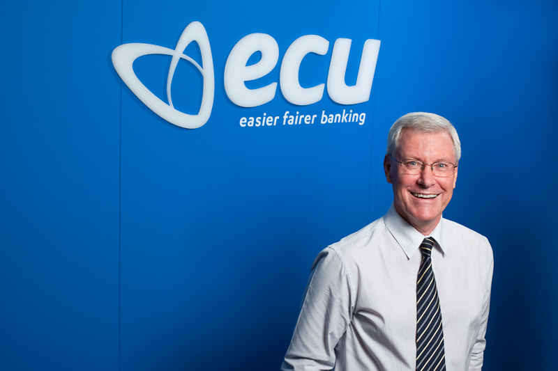 Portrait of banking CEO standing in front of company logo