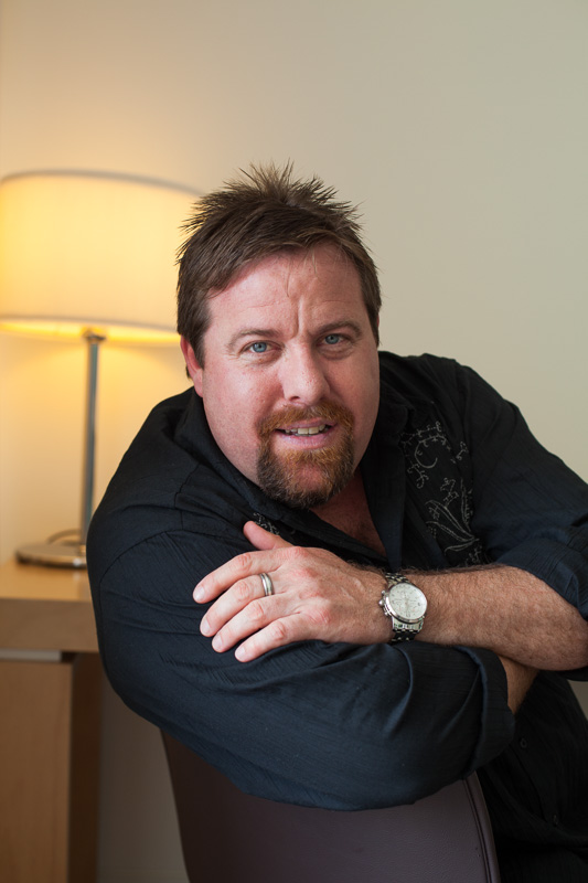Portrait of actor Shane Jacobson sitting on chair, Cairns