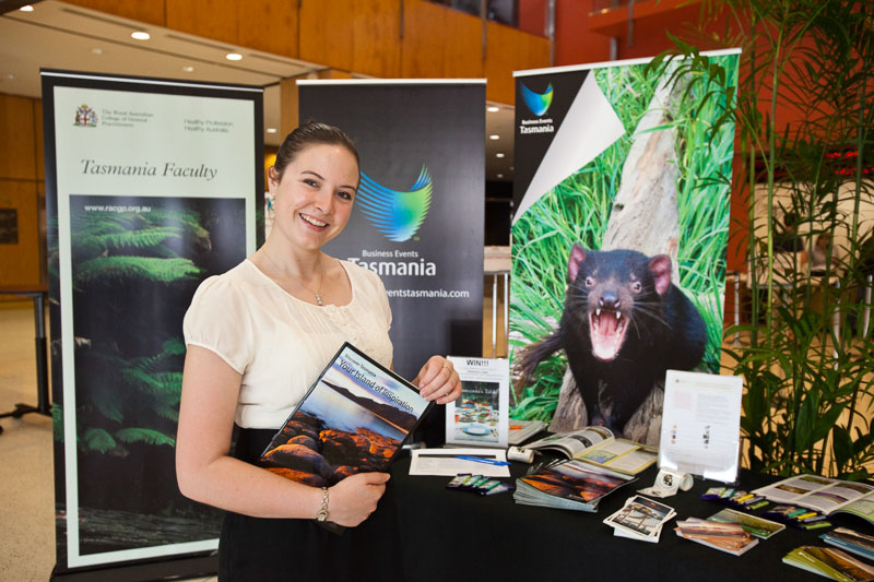 RACGP staff member with brochures at booth at the GP10 Convention, Cairns