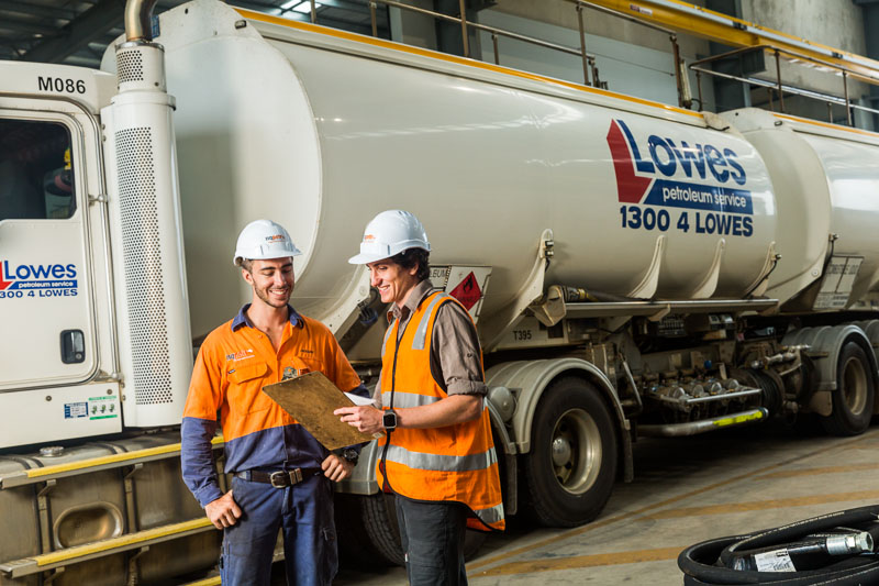Two workers looking at maintenance checklist with a fuel tanker behind, Cairns