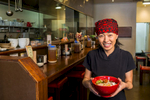 Image of Japanese noodle business owner holding a bowl or ramen noodles