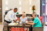 A kitchen staff member serving residents and family at an aged care centre