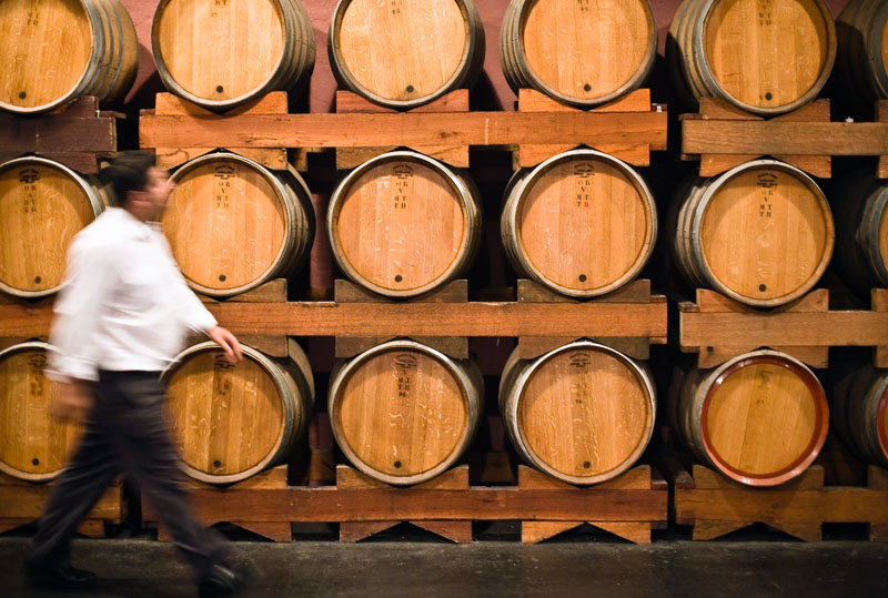 A worker walks past rows of oak barrels at Wyndham Estate in the Hunter Valley