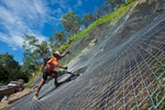 Worker securing mesh on a slope stabilization project, Cairns