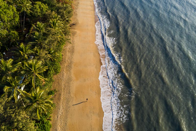 Aerial view of person walking along deserted tropical beach at Palm Cove, Cairns