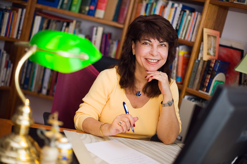 Portrait of female author smiling and sitting at home office desk  