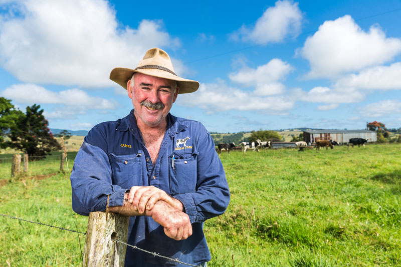 Portrait of dairy farmer leaning on fence post in paddock