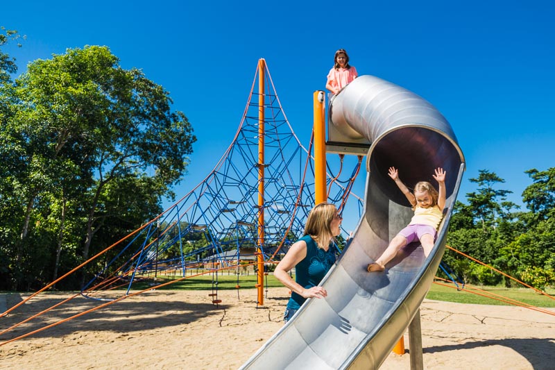 A mother watching on as her kids play on a playground slide