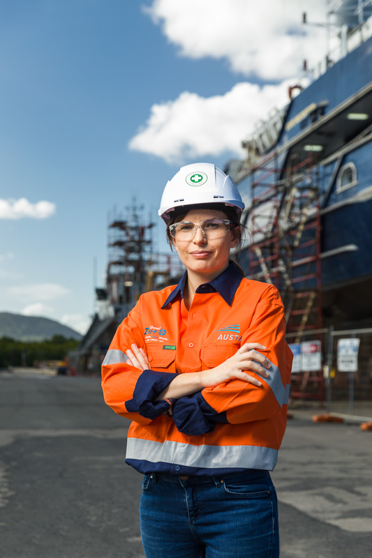 Image of a female safety officer in front of a ship in drydock, Cairns