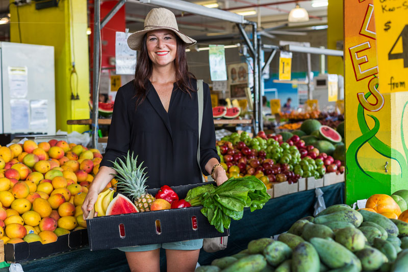 Young woman holding a tray of fruit and vegetables in Rustys Markets, Cairns
