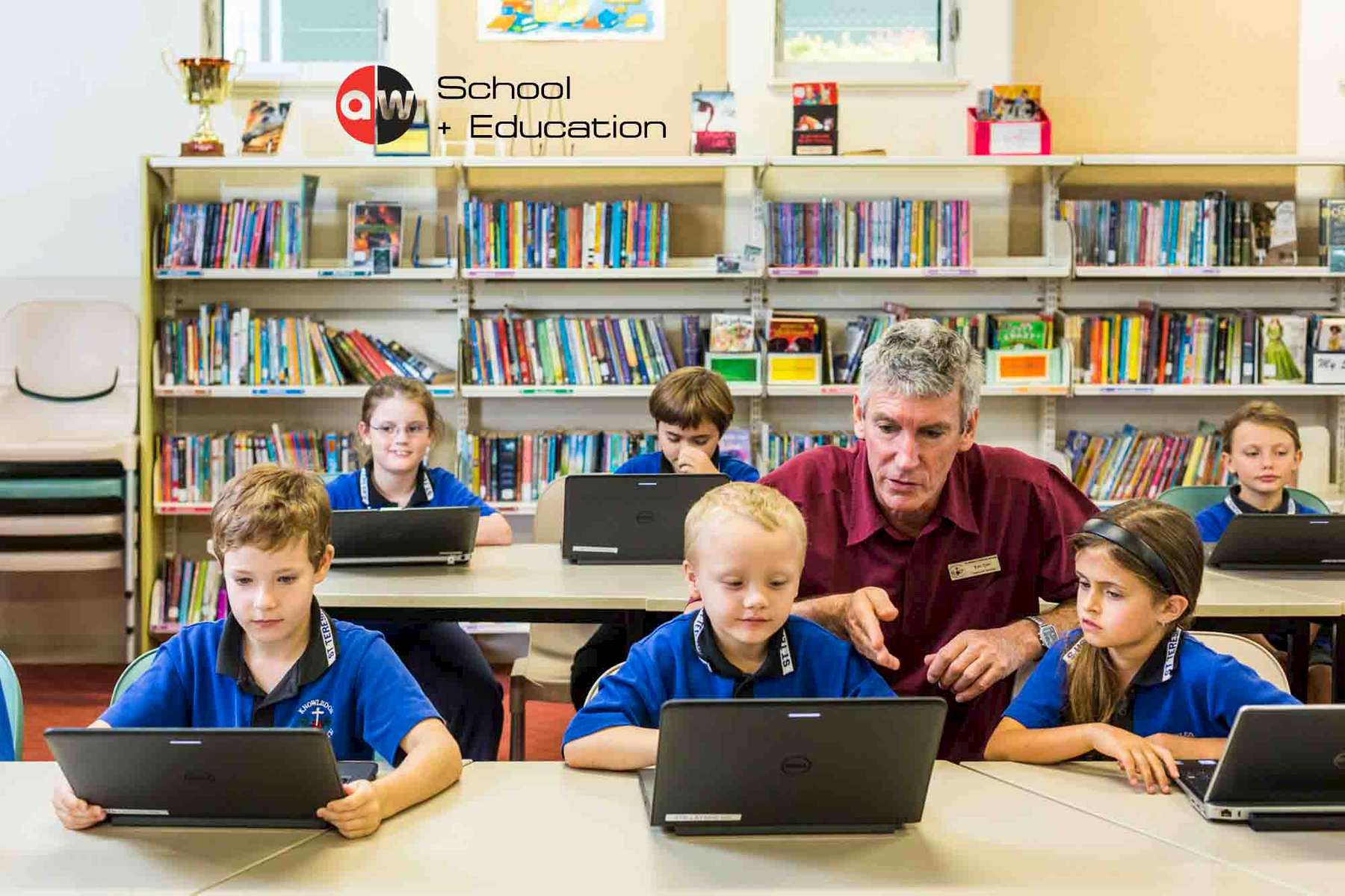 A teacher helping kids working with laptops by photographer in Cairns