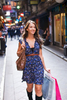 Fashionable young woman walking down city laneway carrying shopping bags