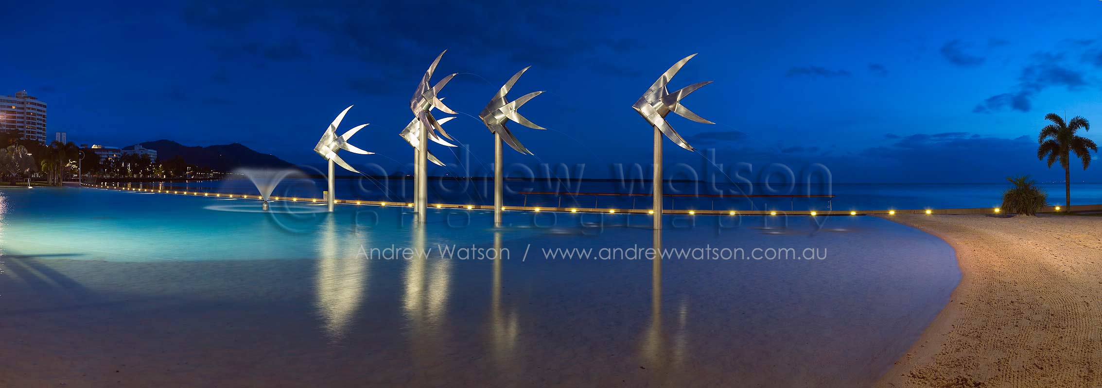 Panoramic image of fish sculpture in the Cairns Esplanade Lagoon at twilight.