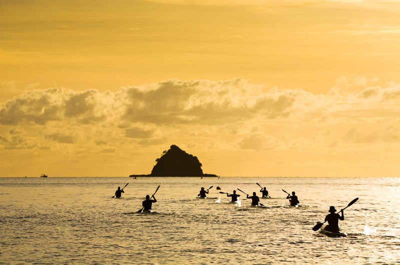 Kayakers silhouetted by the morning sun paddling out to Haycock Island 