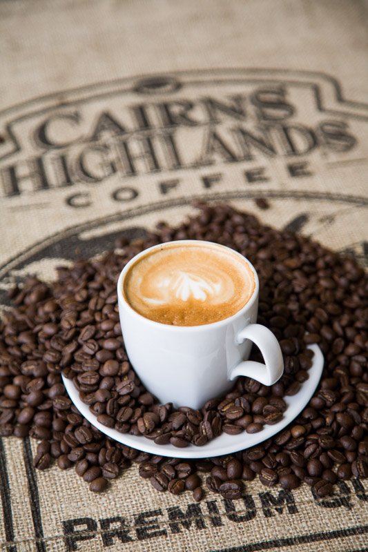 A cup of coffee and roasted coffee beans from the Cairns Highlands