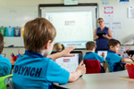 View over shoulder of young student learning maths on an iPad with teacher looking on