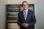 Environmental portrait of male lawyer in front of bookshelf, Cairns
