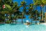 Woman swimming in resort pool overlooking palms trees and beach at Palm Cove by photographer Cairns
