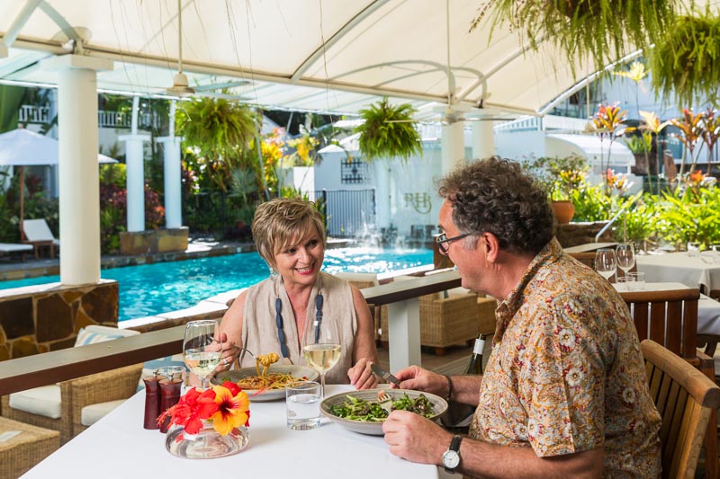 Mature couple dining by the pool at The Reef House, Palm Cove