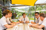 A group of male high school students talking together at a table