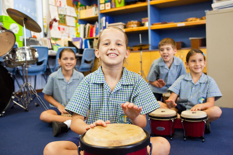 Portrait of happy students playing drums in school music class