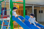 Two school boys having fun on slides in the playground