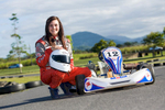 Portrait of young female gocart driver next to cart on racetrack, Cairns