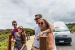 Two young couples laughing and smiling in front of roadtrip campervan