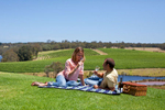 Young couple relaxing on a picnic rug with a wine overlooking the vineyard