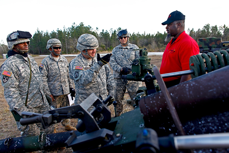 Soldiers speak to an artillery instructor on how to properly use their cannons.