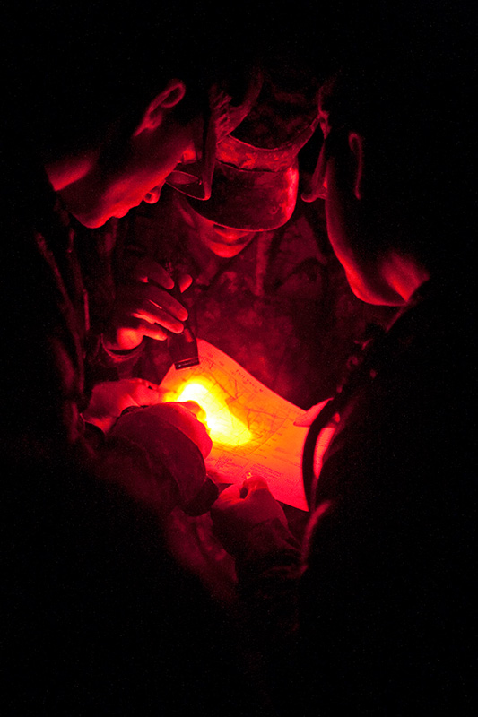 With only the aid of a map and a dim flashlight, Cadets Travis Williams (left), Marquarius Moore (center) and Ian Clark (right) try to determine their location on Sept. 26, 2008. In the night land navigation course, the teams have three hours to find three different points. This event was the first event of a three-day long training session at Fort Knox, Ky.