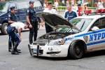 An NYPD officer inspects damage done to a squad card.  The car collided with a Cadillac and spun out of control hitting five pedestrians on E. 6th Street and Avenue D on June 30, 2009.