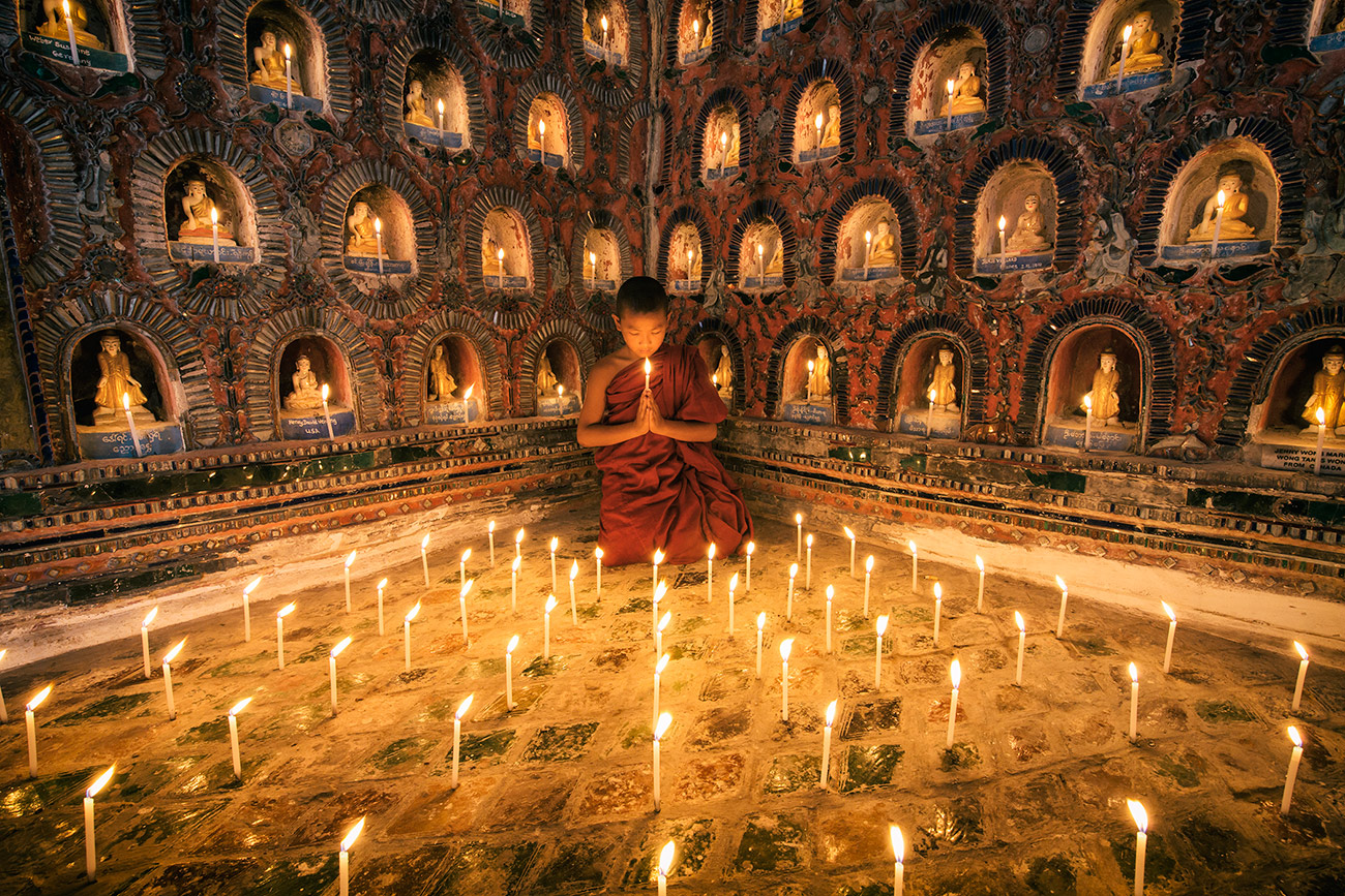 Monk praying by candlelight in his monastery