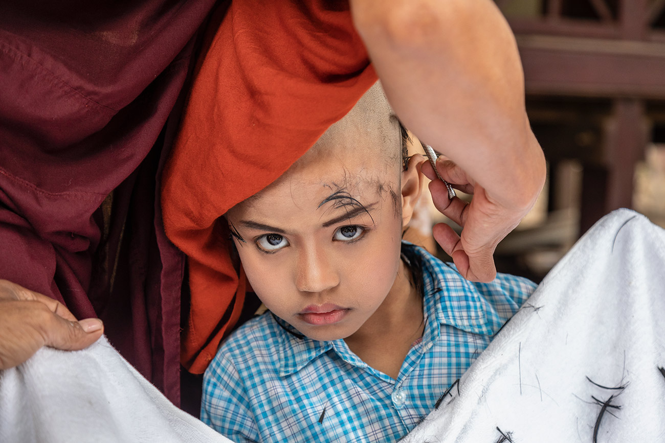 Young monk getting his head shaved in Burma
