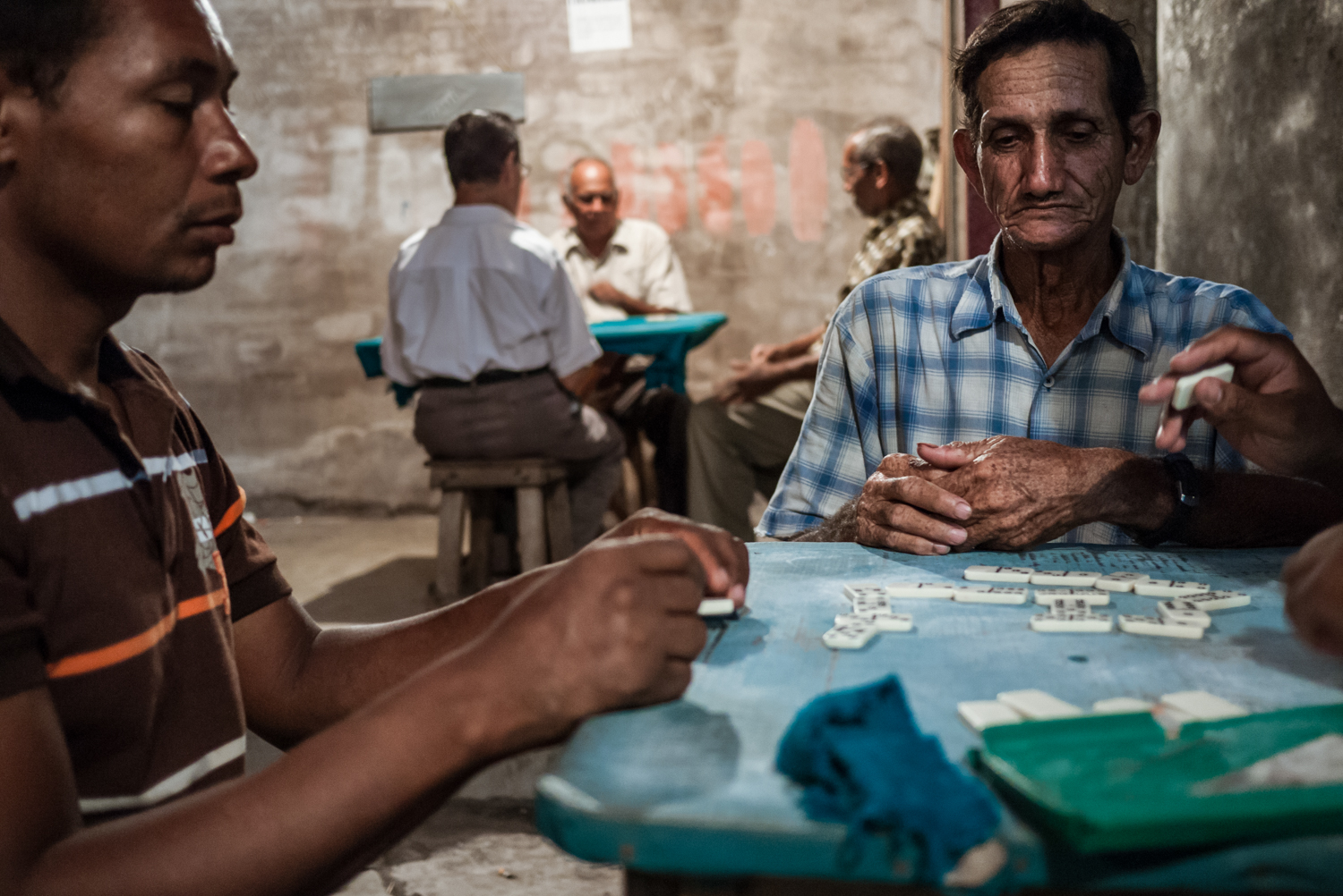 Billares de Rueda. Men playing domino in one of the billares in town. Loud vallenato music records are always played in the background.