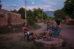 Villanueva, El Cafetal barrio. Girls talk under the rising full moon in El Cafetal barrio, Villanueva, with the Serrania de Perija mountains in the background. While rough hewn and leathery in sound, vallenato lyrics are usually plain written and sugarcane sweet. Everyday events, passion, eternal love, village folklore, travelogues and miracles blur in the telling; voices crack, crackle with emotion in a music that so influenced Gabriel Garcia Marquez that he once described One Hundred Years of Solitude as a 350 page vallenato and inspired charcters such as {quote}.Remedios la Bella{quote}. Vallenato translates as “born in the valley” and originated  from farmers who mixed Spanish and West African rhythms, vallenato was long derided across Colombia as unsophisticated cowboy music, before it was championed by the country’s intelligentsia.