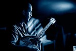 This is an intimate, moody, high contrast photograph of a man named George playing his bouzouki on the balcony.
