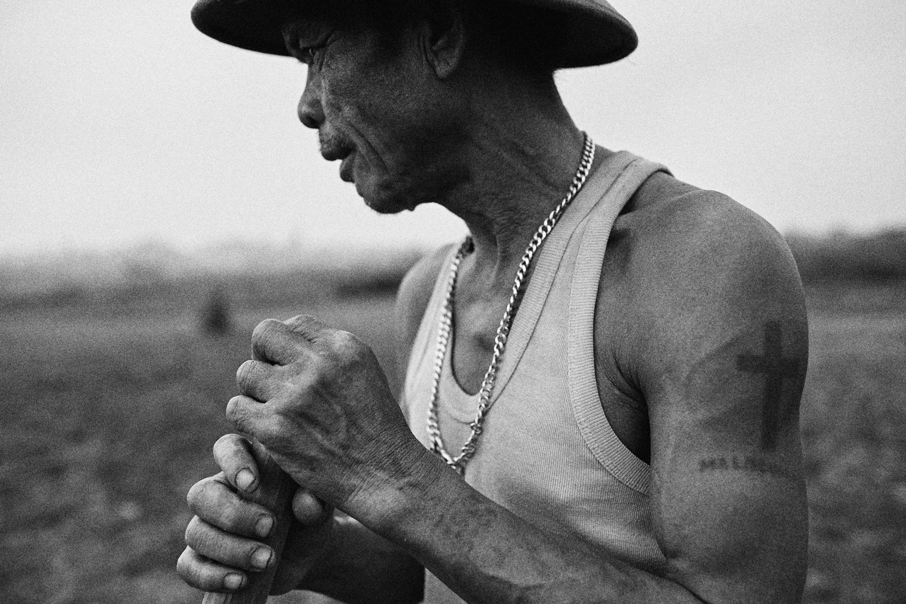Farmer Nguyen Van Duoc works his fields beneath Long Bien Bridge in Hanoi, Vietnam. He earns roughly US$60 a month to support his wife and four children and he bears a tattoo that roughly translates as: {quote}I'm poor. I hate it{quote}.