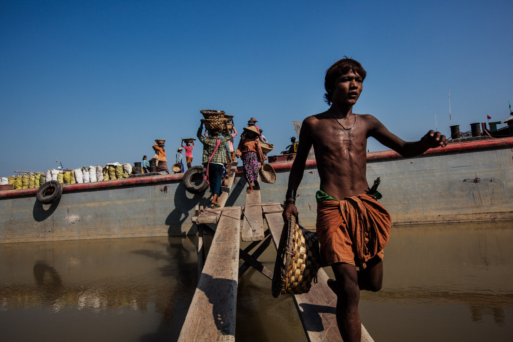 Burmese laborers load stones onto a large barge awaiting transport to construction sites downriver from Mandalay.