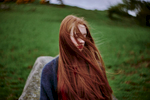 The wind swirls a woman's hair in the countryside of northern Scotland.