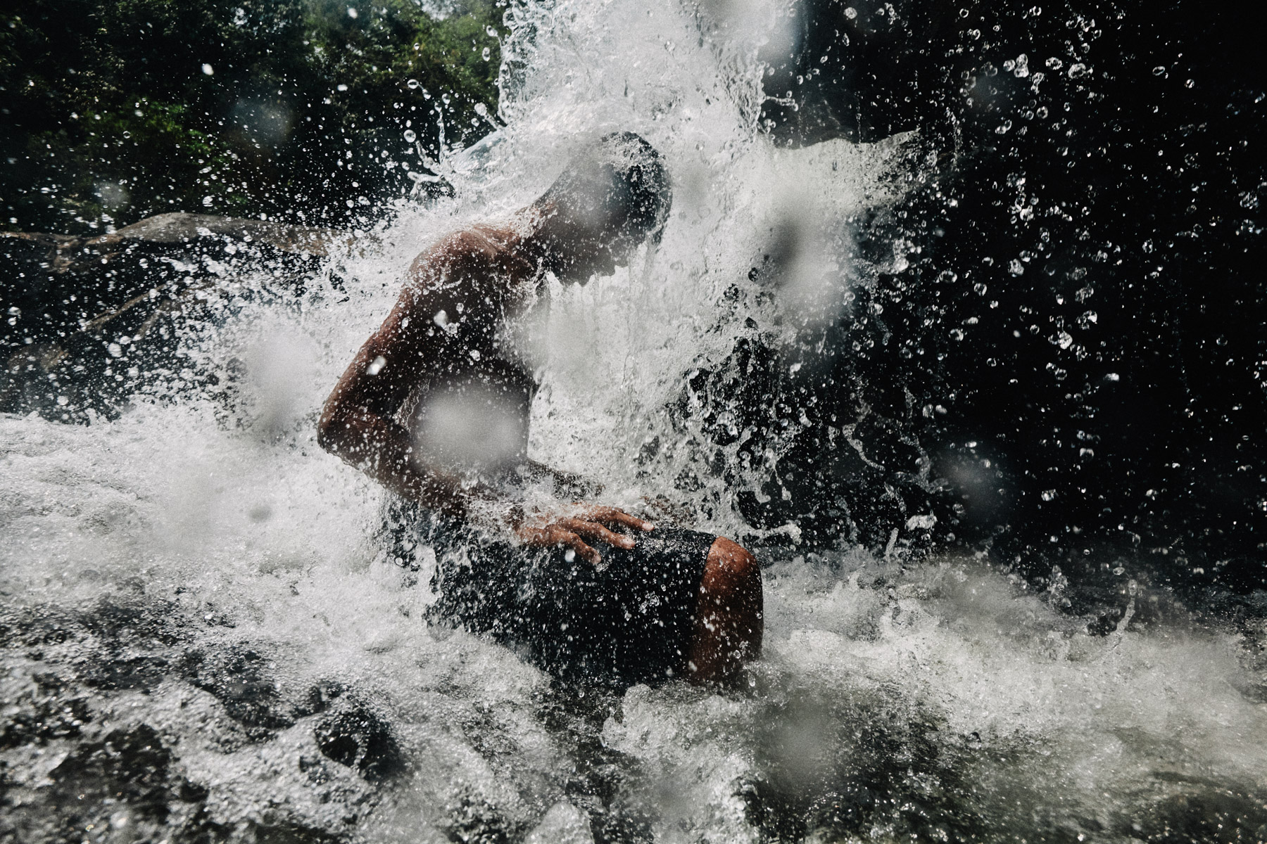 A young man gets splashed by a waterfall in Koh Kong, Cambodia.