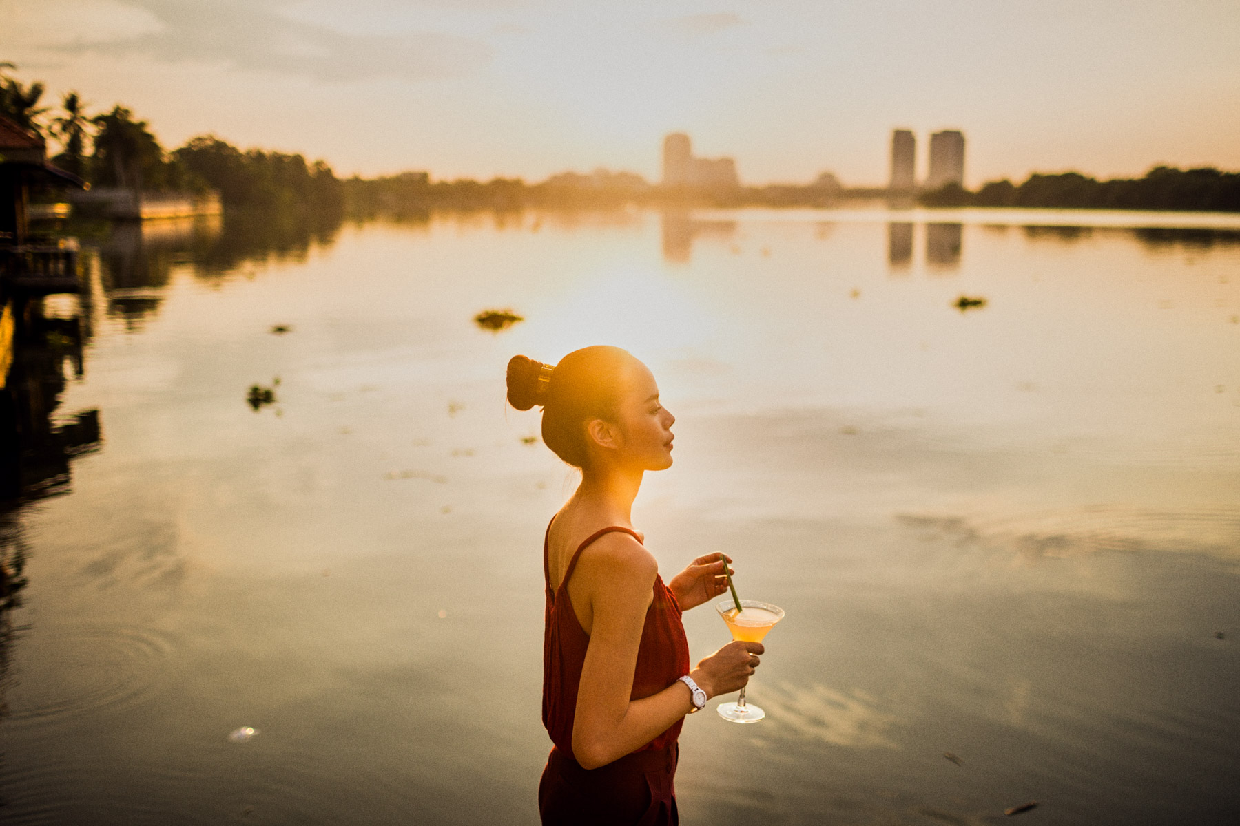 A young woman stirs a cocktail on the banks of the Saigon River.