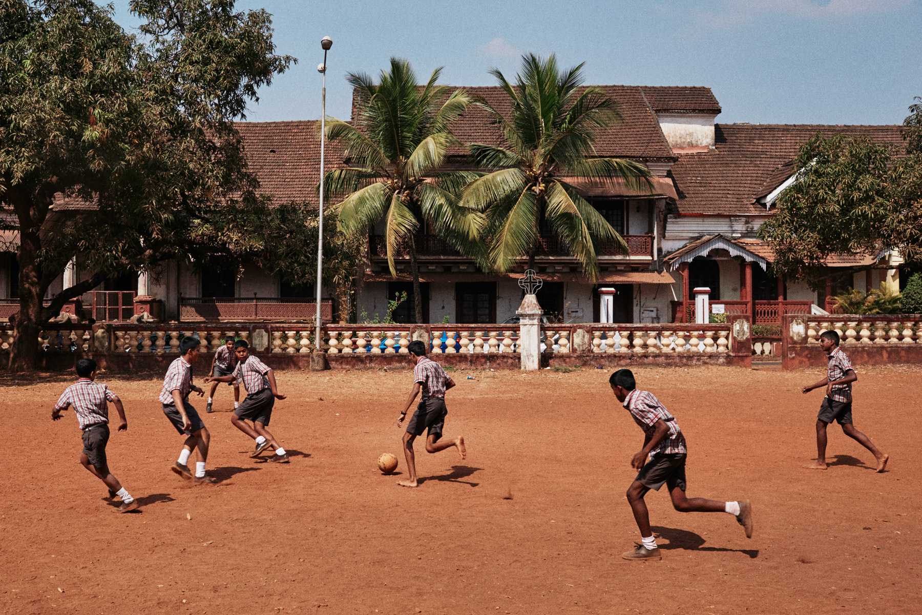 Schoolboys play a game of football in a dirt lot in Margao, India.