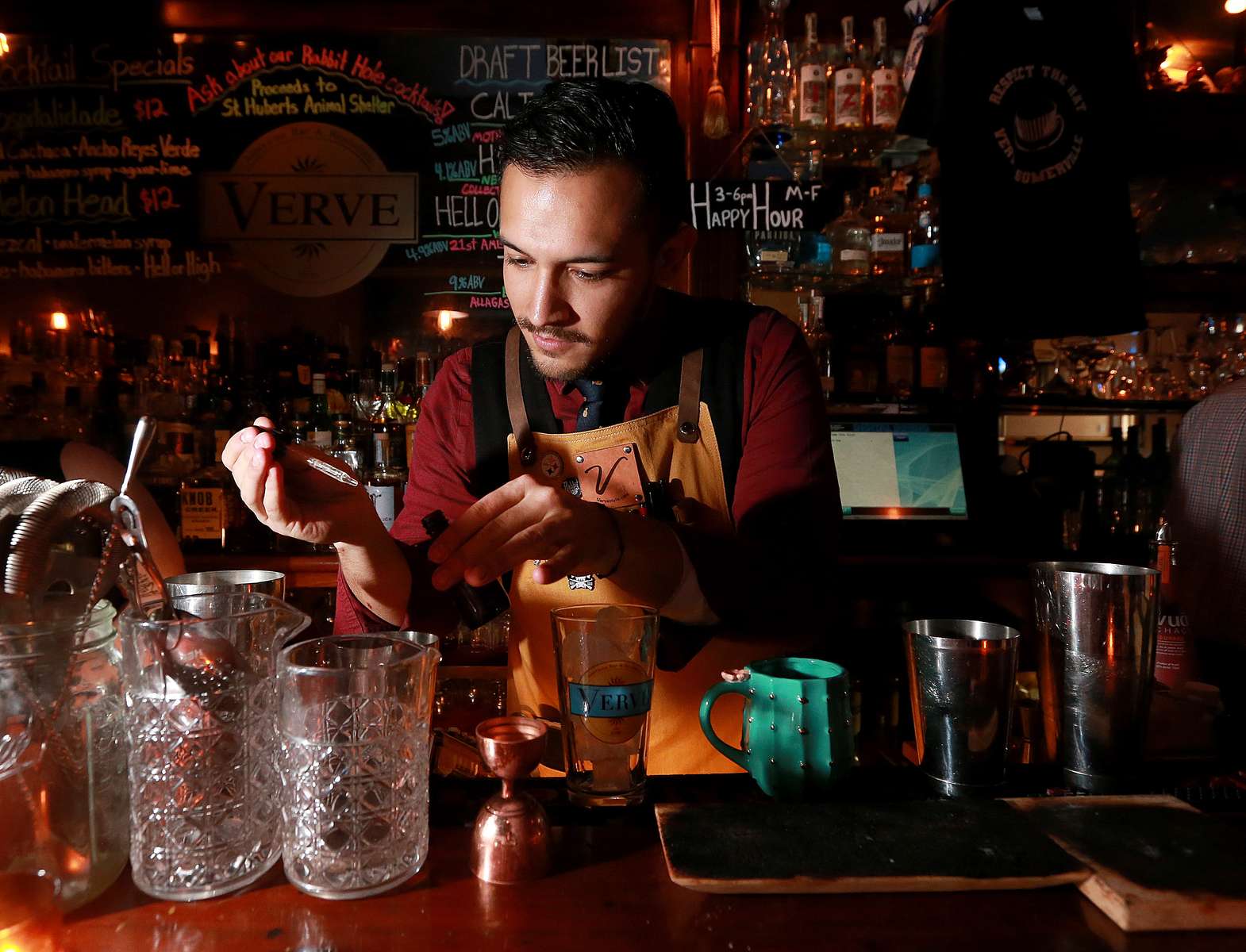 Bartender Roger Aquino makes a cocktail using a dropper to add flavor at Verve restaurant and bar in Somerville.