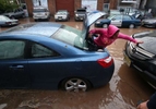 Neidy Lozano tries to get out of her car after a water main broke at Park Ave and North 5th Street causing flooding that damaged cars and homes on Monday, in Newark.
