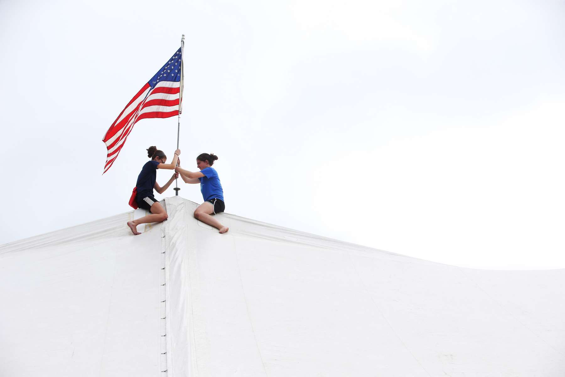 Ariel Staffin and Alanna Staffin try to post the American flag on one of the fair tents as the 69th Somerset County 4-H fair opened today at the North Branch Park 4-H Fairgrounds on Milltown Road in Bridgewater.
