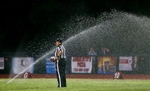 A referee stays on the football field as teh sprinklers turned on during the game.