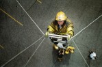 A firefighter climbs a ladder held up by just ropes as a trust building exercise.